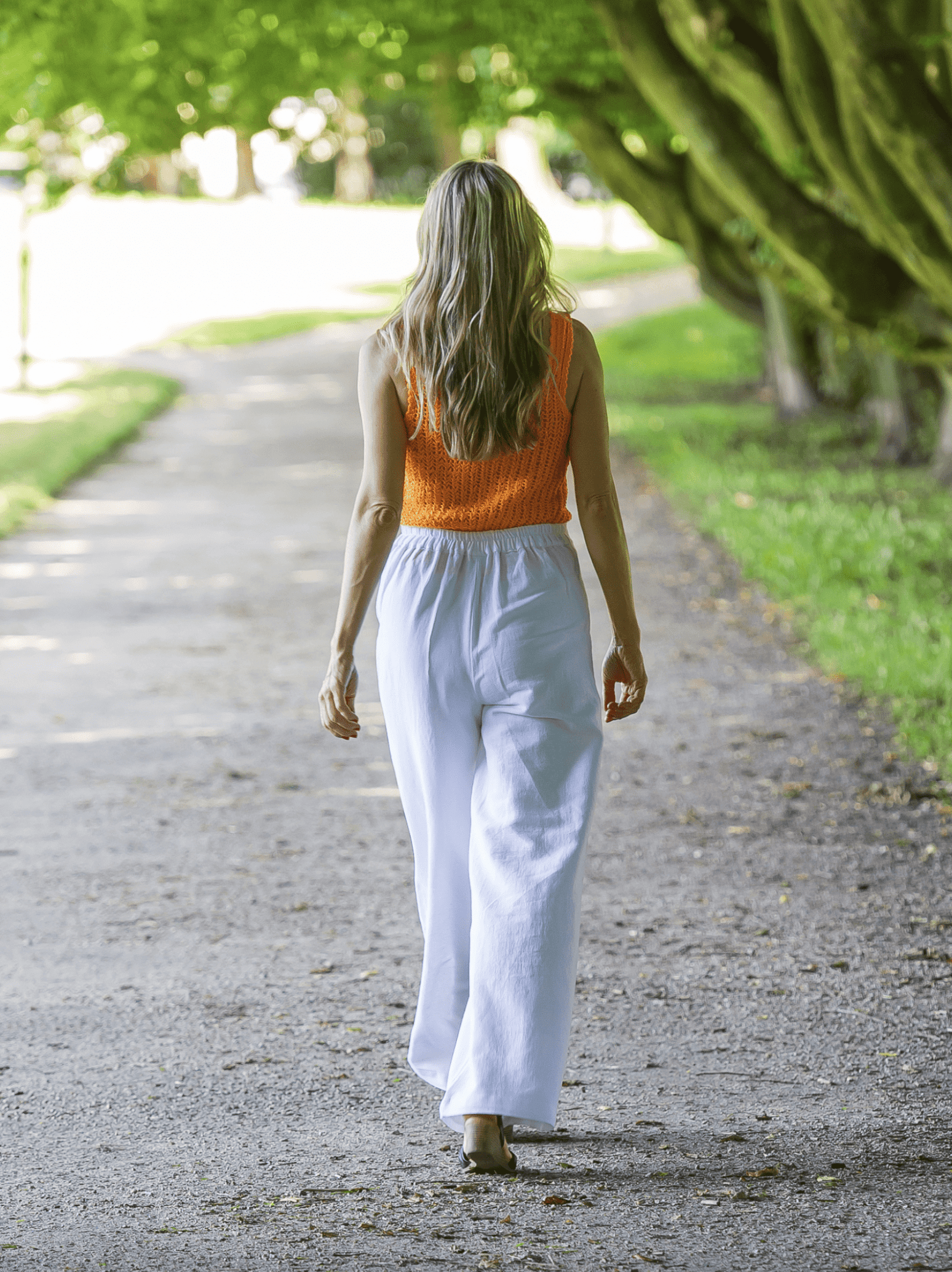 Modelka w białych spodniach konopno-bawełnianych z gumką w pasie, stylizacja letnia.